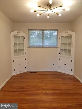 an empty room with wooden floor cabinet and windows