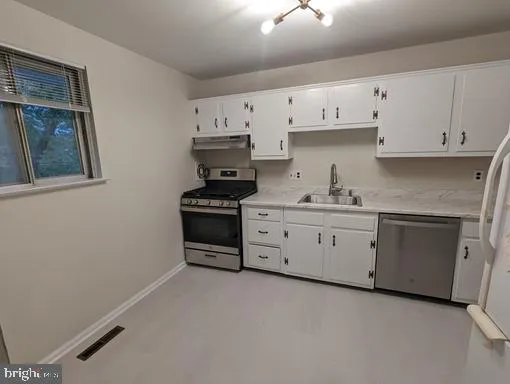 a kitchen with stainless steel appliances a stove a sink and white cabinets