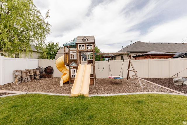 972 West 2840th Street South Logan, UT 84321 - Photo 34 of 46 Expansive backyard featuring a manicured lawn, white vinyl fencing, and a dedicated play area with wood chip ground cover