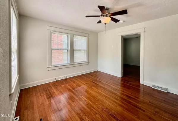 an empty room with wooden floor and windows