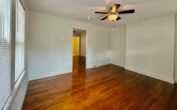 a view of empty room with wooden floor and fan