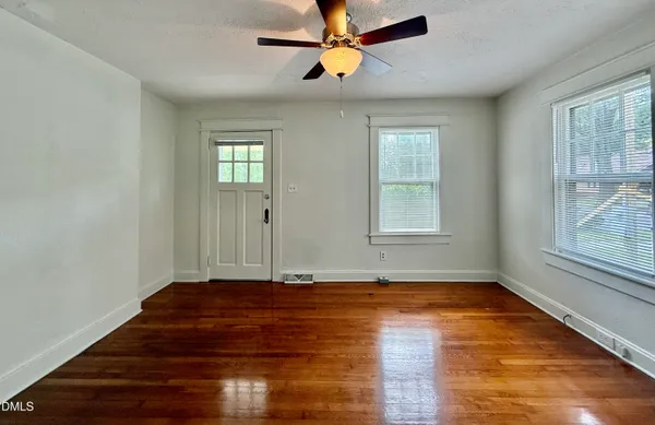 a view of empty room with wooden floor and fan