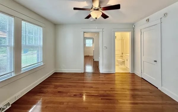 a view of an empty room with window and wooden floor