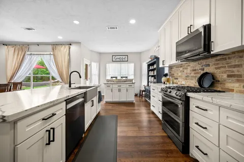 a kitchen with stainless steel appliances kitchen island granite countertop a refrigerator a stove and a dining table with wooden floor