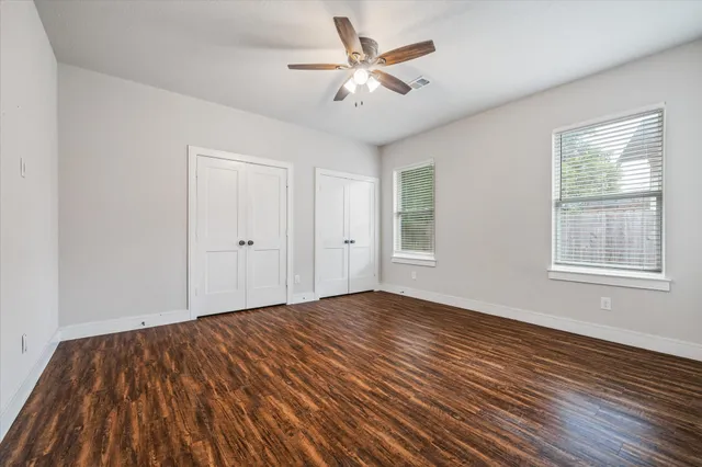 a view of empty room with wooden floor and fan