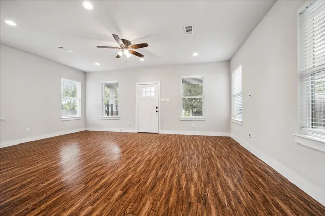 a view of empty room with wooden floor and fan
