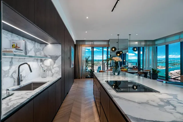 a kitchen with kitchen island granite countertop a sink a counter top space and stainless steel appliances