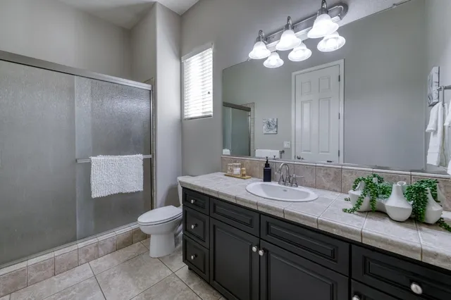 a bathroom with a granite countertop sink a toilet and a mirror