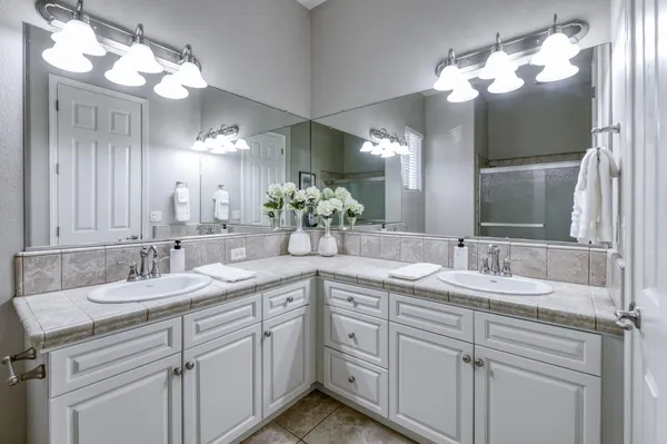 a bathroom with double vanity sinks a vanity a lamp and a mirror