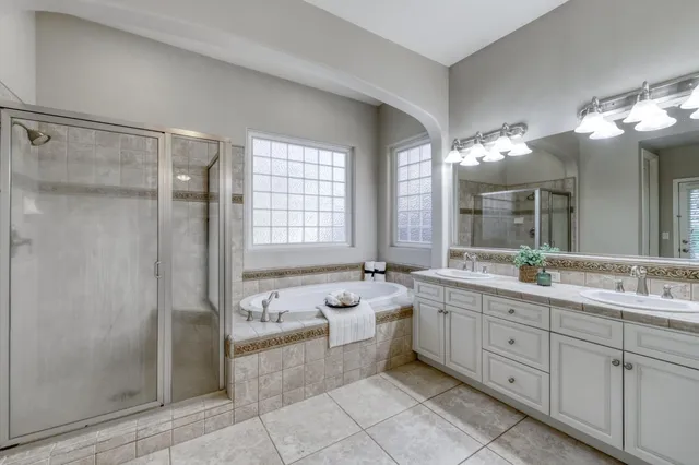 a spacious bathroom with a double vanity sink a large mirror and a shower