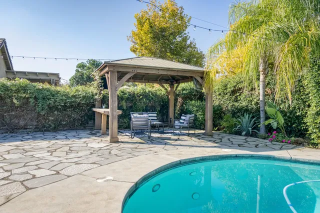 a view of a patio with table and chairs under an umbrella with a small garden