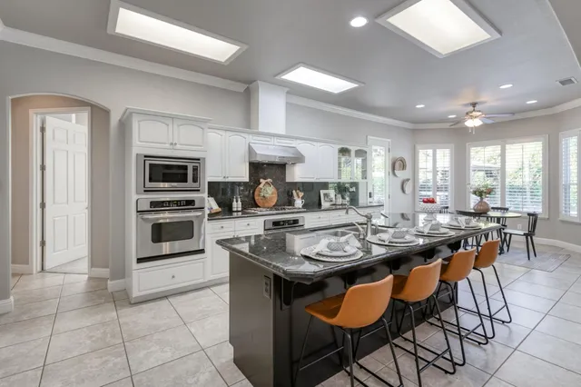a kitchen with stainless steel appliances granite countertop a stove a sink a microwave a dining table and chairs