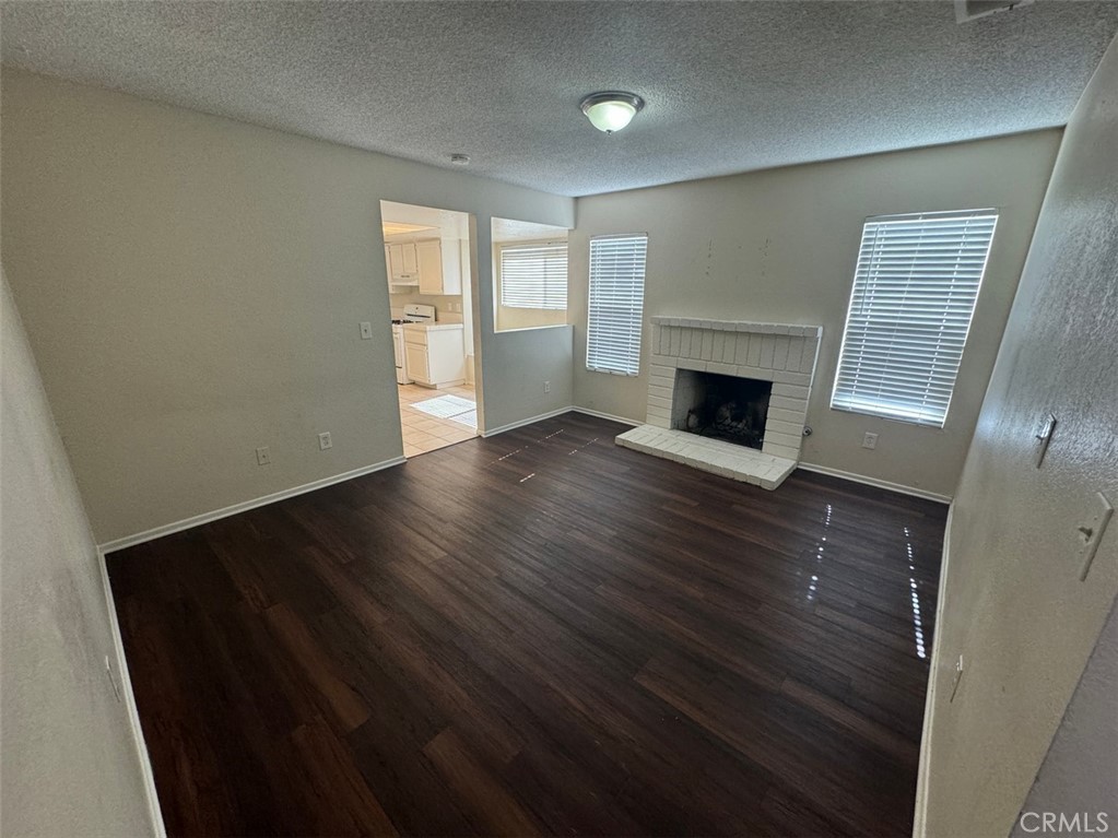 13080 Mohican Drive Moreno Valley, CA 92555 - Photo 15 of 38 an empty room with wooden floor fireplace and windows