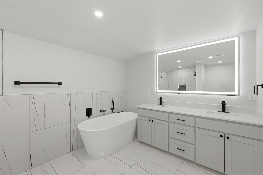 502 Madison Street Cleburne, TX 76033 - Photo 17 of 30 Gorgeous fully remodeled primary bath with led mirror, double vanities, free standing tub, and large beautifully tiled walk-in-shower.