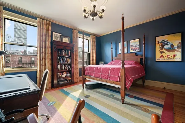 a bedroom with a bed table chair and a window