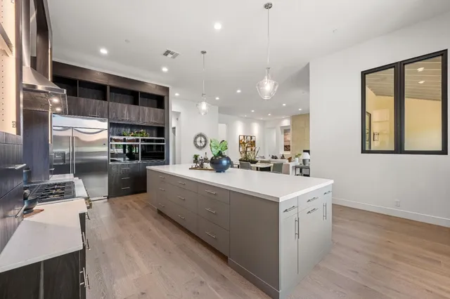 a large kitchen with stainless steel appliances a large counter top a stove a chimney a sink and a refrigerator