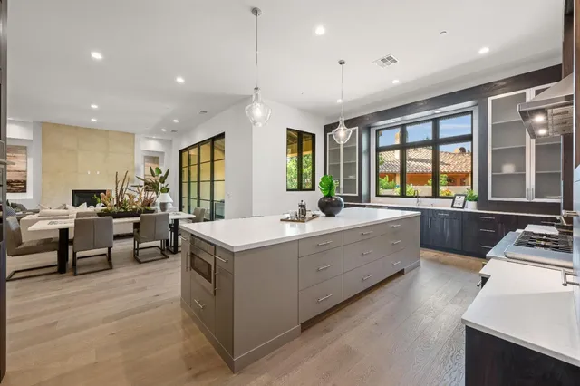 a large kitchen with stainless steel appliances a large counter top a sink a stove and a refrigerator