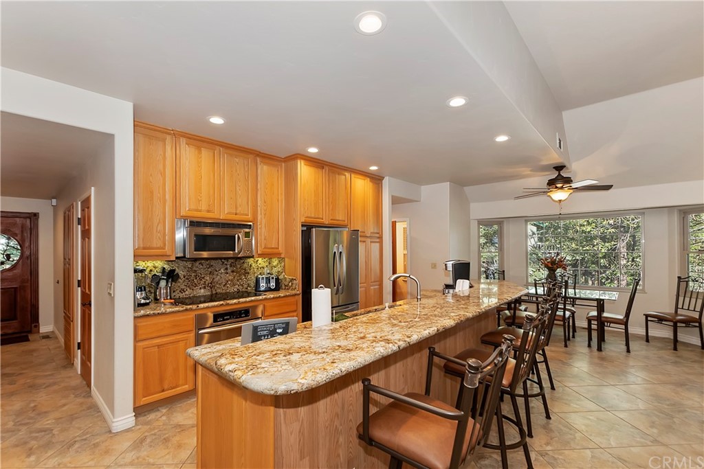 24310 Albrun Drive Crestline, CA 92325 - Photo 11 of 39 a kitchen with stainless steel appliances kitchen island granite countertop a stove a refrigerator a kitchen island a dining table and chairs with wooden floor