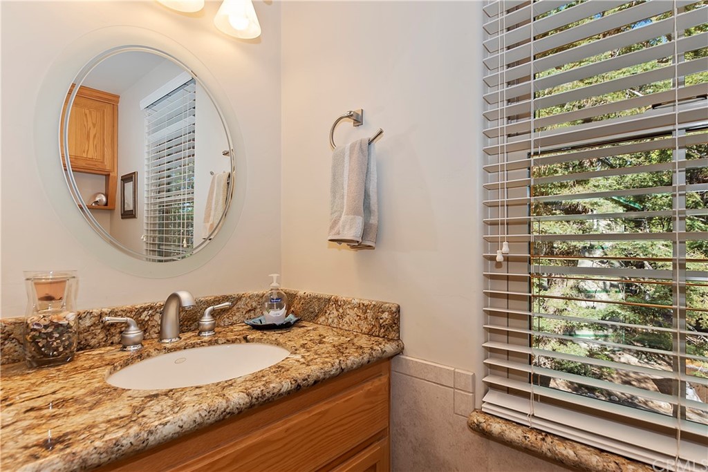 24310 Albrun Drive Crestline, CA 92325 - Photo 13 of 39 a bathroom with a granite countertop sink and a mirror