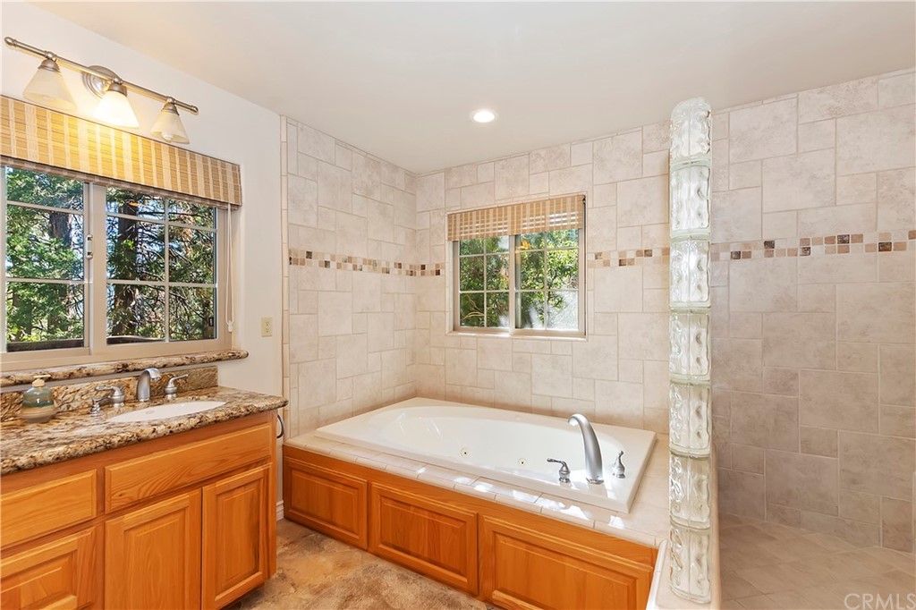 24310 Albrun Drive Crestline, CA 92325 - Photo 19 of 39 a bathroom with a granite countertop tub sink and mirror