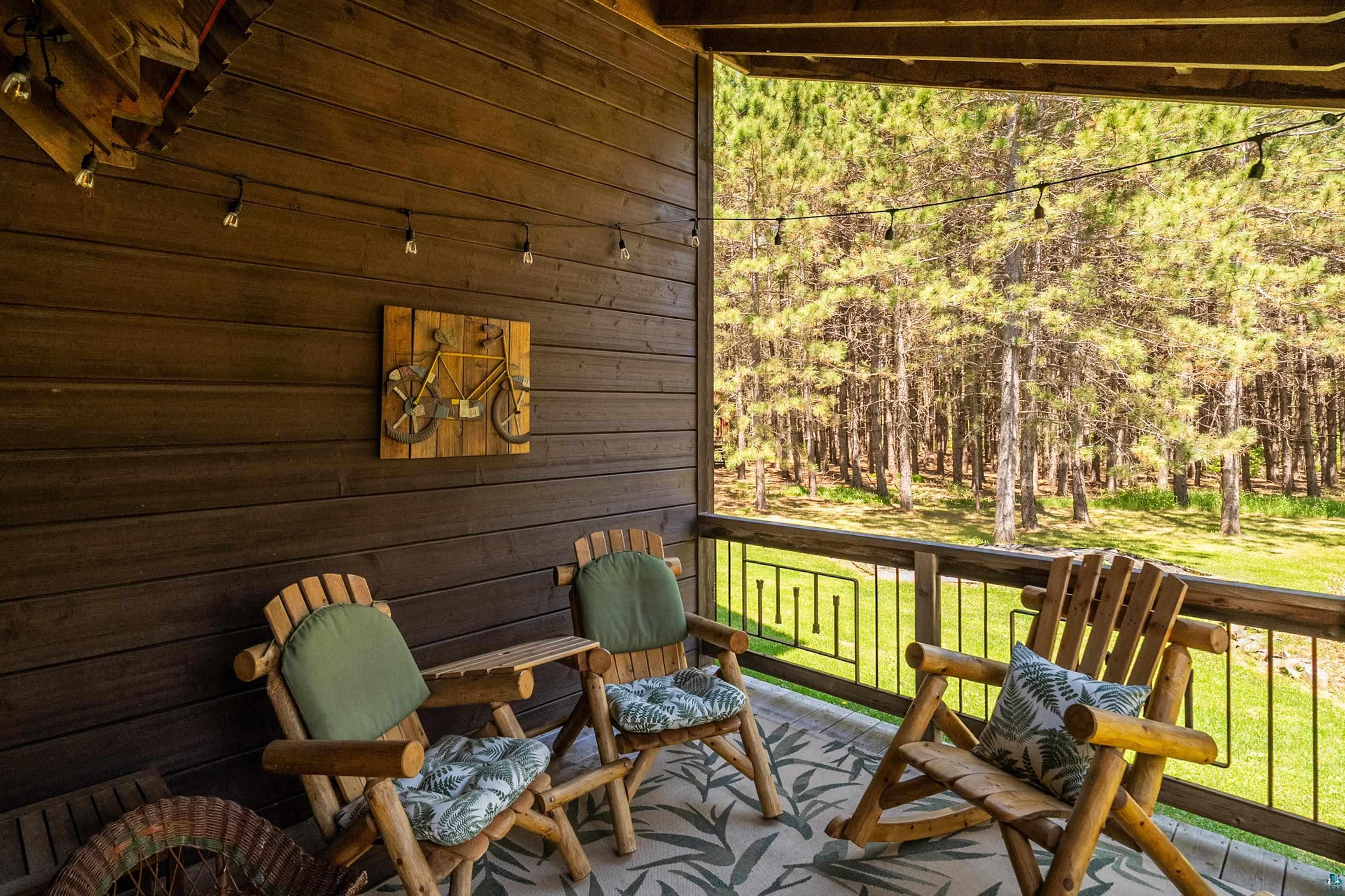 75 East Stark Road Esko, MN 55733 - Photo 6 of 87 Covered porch featuring dark wood paneling, string lighting, and wood-finish railings with geometric metal inserts