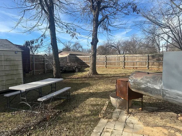 a view of backyard with wooden fence and a large tree