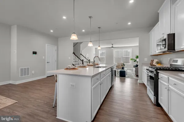 a large kitchen with stainless steel appliances a sink a stove and a wooden floors