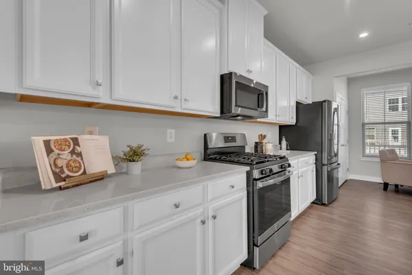 a kitchen with stainless steel appliances granite countertop white cabinets a refrigerator a stove a sink and a hard wood floors