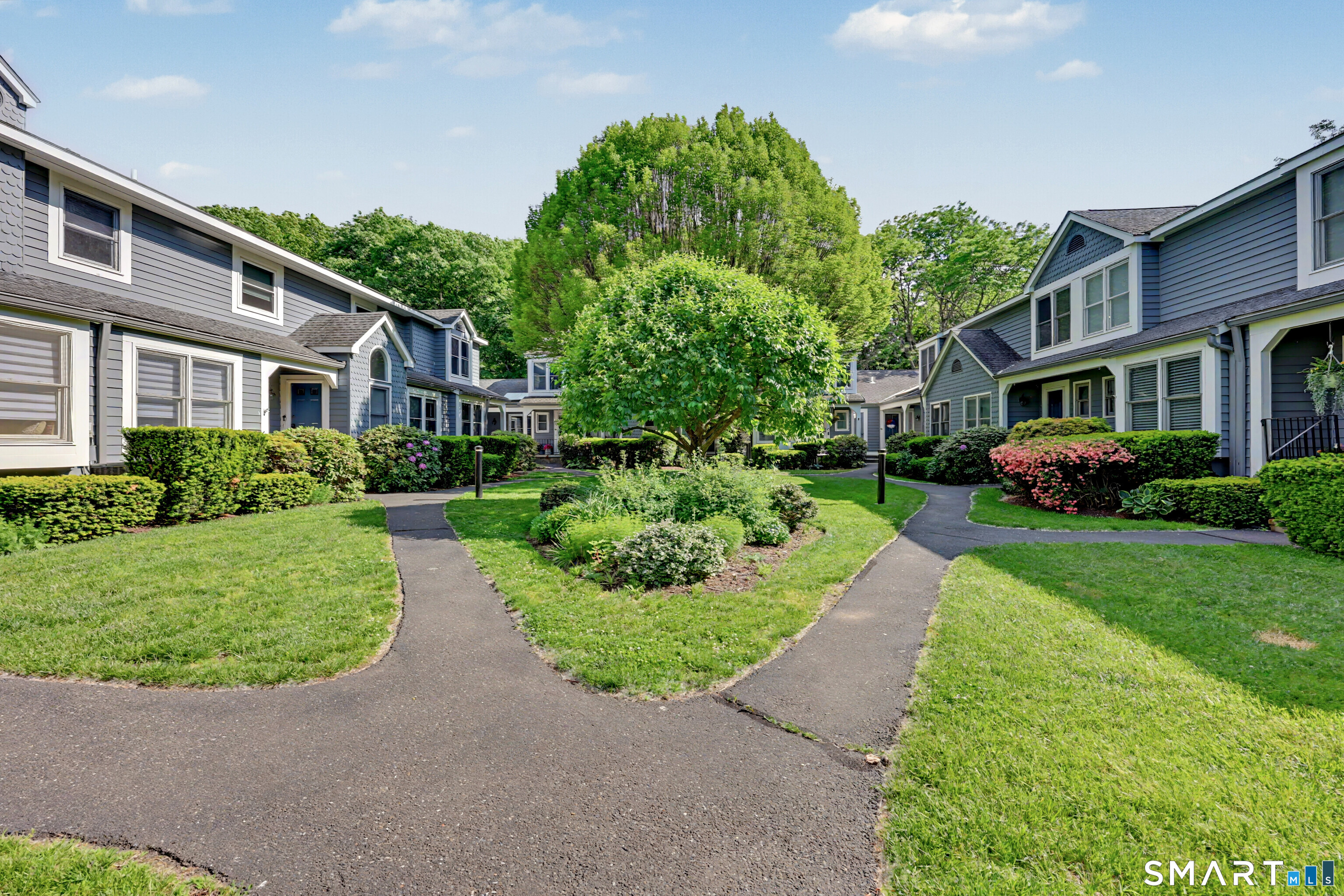 70 Fawn Ridge Lane, Unit 70 Norwalk, CT 06851 - Photo 1 of 36 a front view of a house with a yard and potted plants