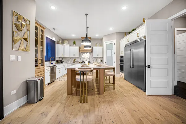 a kitchen with kitchen island granite countertop a center island a stove a refrigerator and a wooden floor