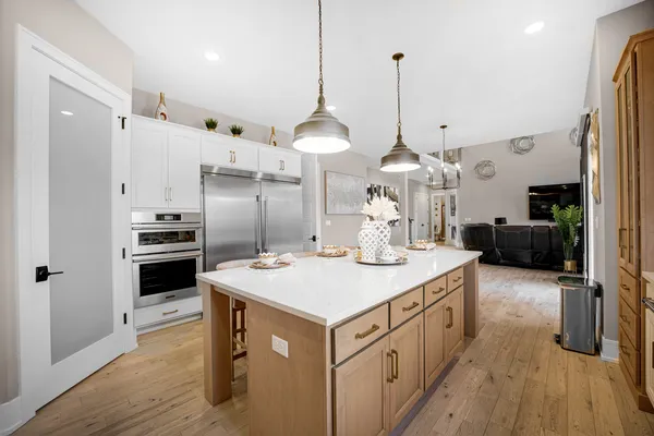 a kitchen with stainless steel appliances granite countertop a stove a sink a refrigerator and a dining table with wooden floor