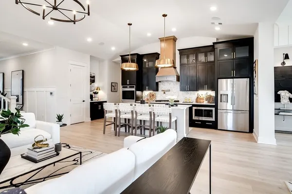 a kitchen with stainless steel appliances kitchen island granite countertop a stove a refrigerator a oven a sink with a dining table and chairs with wooden floor