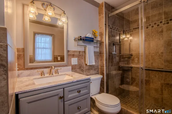 a bathroom with a granite countertop sink toilet a shower and a mirror