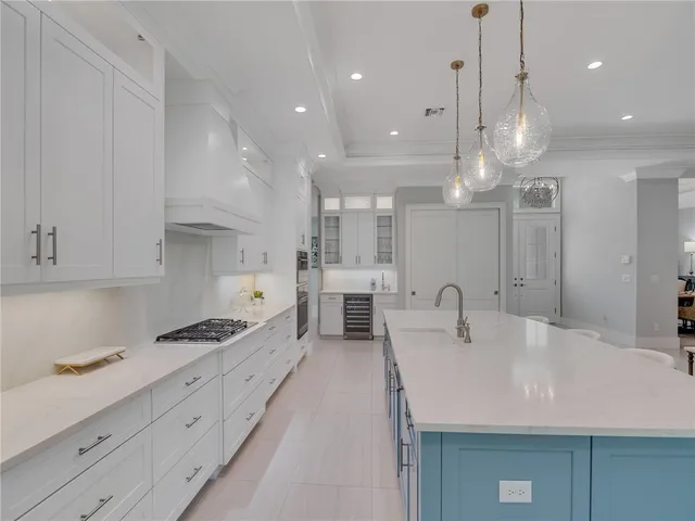 a very nice looking kitchen with granite countertop a stove a sink a refrigerator and white cabinets