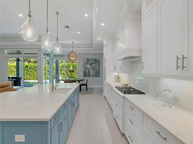 a kitchen with granite countertop a stove a sink a center island and windows