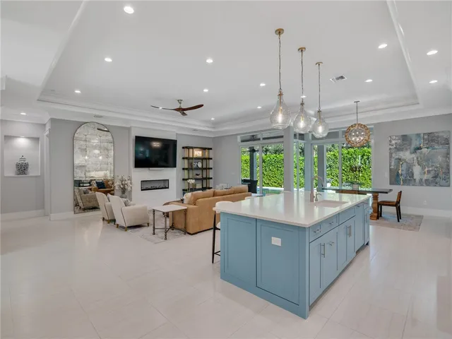 a kitchen with kitchen island a large counter top space appliances and a living room view
