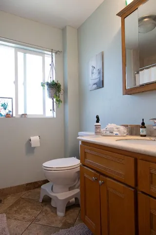 a bathroom with a granite countertop toilet sink and mirror