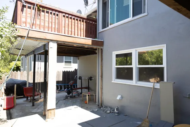 a view of a house with a barbeque and bench