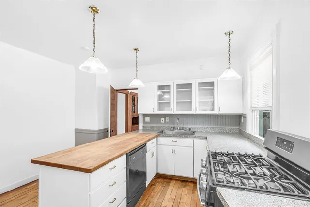 a kitchen that has a sink a stove and a wooden floor