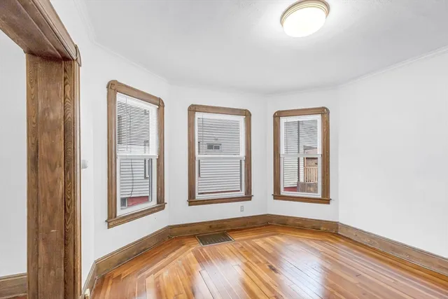 a view of an empty room with window and wooden floor