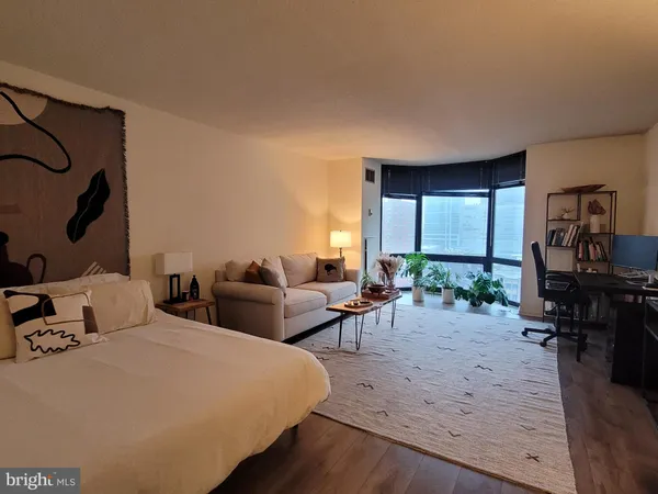 a living room with furniture a large window and wooden floor