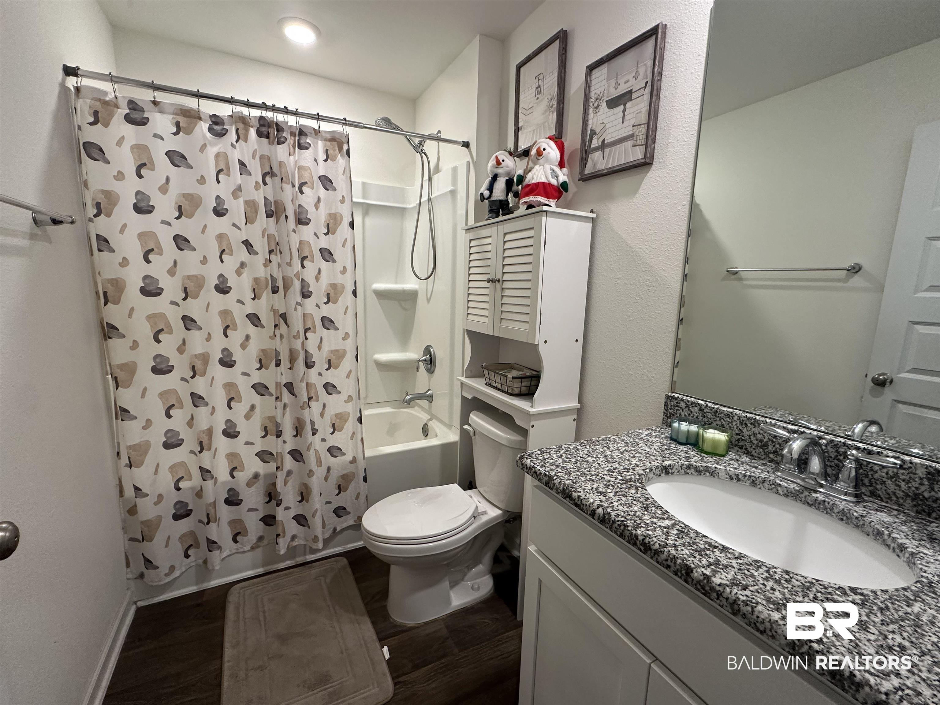 23792 Unbridled Loop Daphne, AL 36526 - Photo 30 of 36 Bathroom with vanity, shower / bathtub combination with curtain, dark wood-style flooring, and a textured wall