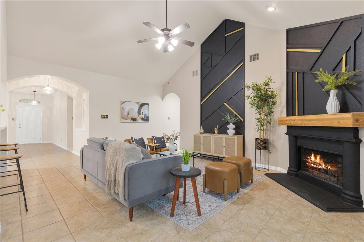 2501 Aspen Meadow Road Leander, TX 78641 - Photo 7 of 30 Vaulted living area featuring a black fireplace with a light wood mantel, tile flooring, and a ceiling fan