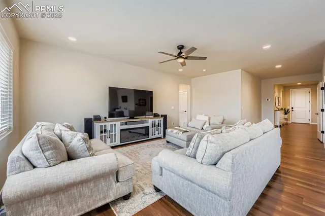 a kitchen with stainless steel appliances kitchen island granite countertop a refrigerator a stove a sink a dining table and chairs with wooden floor