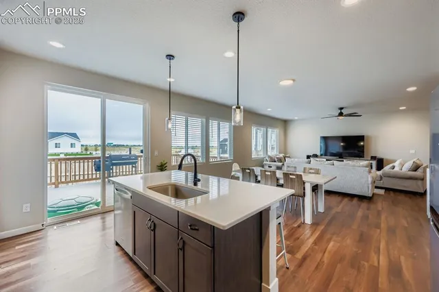 a kitchen with stainless steel appliances granite countertop a stove top oven a sink dishwasher a dining table and chairs with wooden floor