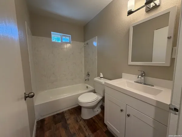 a bathroom with a toilet a sink a mirror a bathtub and vanity