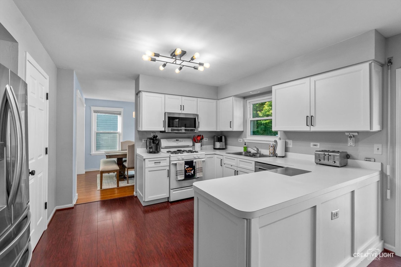 895 Lowell Lane Naperville, IL 60540 - Photo 9 of 40 a kitchen with a sink dishwasher a stove a refrigerator and a dining table with wooden floor