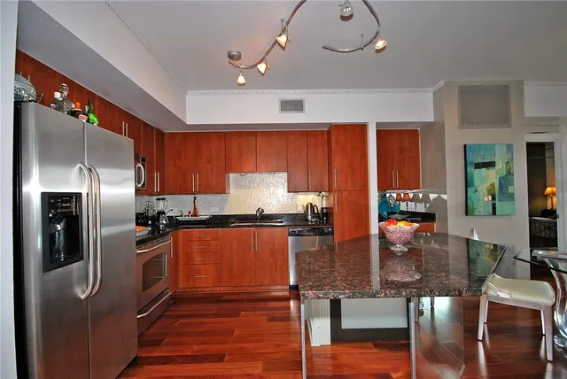 a kitchen with stainless steel appliances granite countertop a stove refrigerator and wooden cabinets