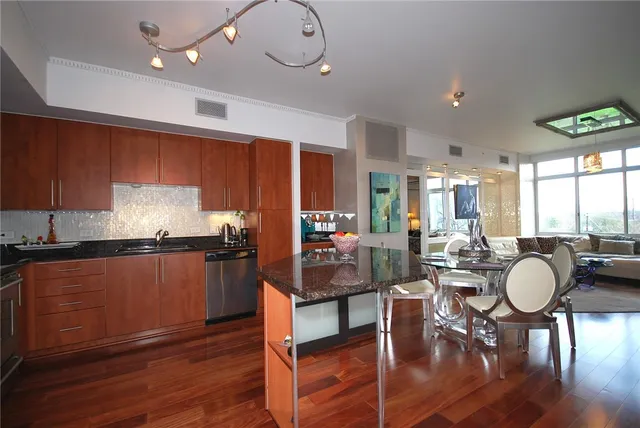 a kitchen with granite countertop a stove a sink a dining table and chairs with wooden floor