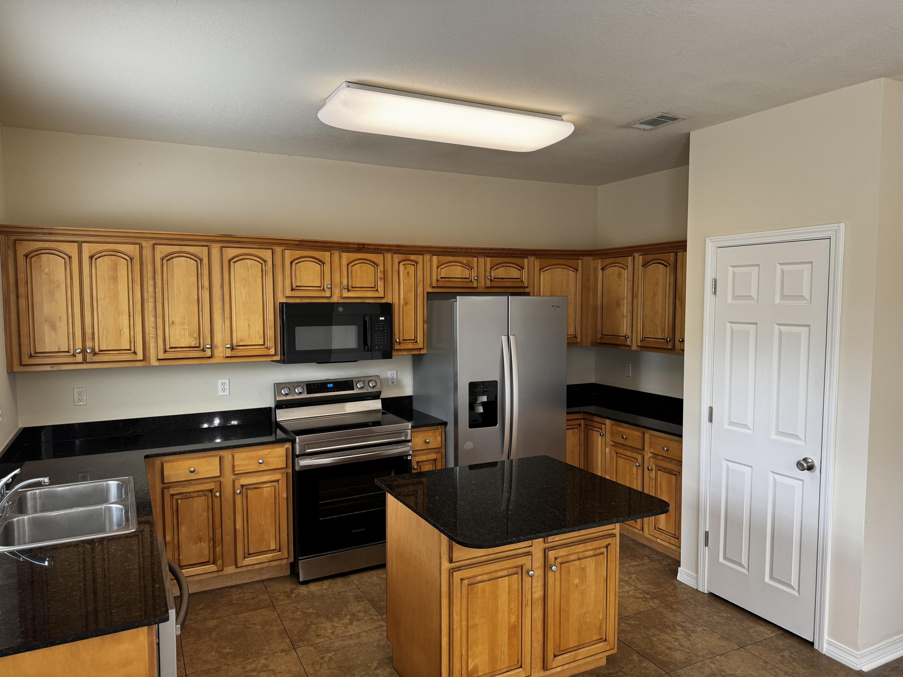a kitchen with granite countertop a refrigerator and a stove top oven